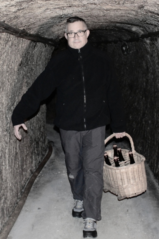 Jérôme Portier marchant dans une cave et portant un panier rempli de bouteille